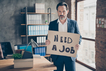 Portrait of his he serious jobless guy realtor economist holding in hands placard saying need a job...