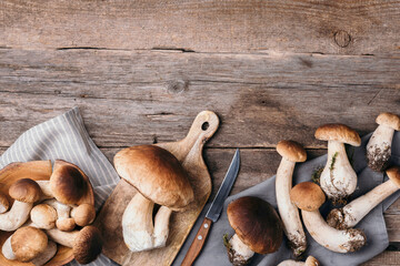 Fresh forest boletus mushrooms on wooden background. Top view. Copy space. Autumn harvest concept. Fresh picked Porcini mushrooms in basket