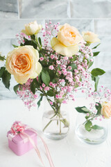 Obraz na płótnie Canvas bouquet of peach spray roses and gypsophila and pink gift box on a white table..