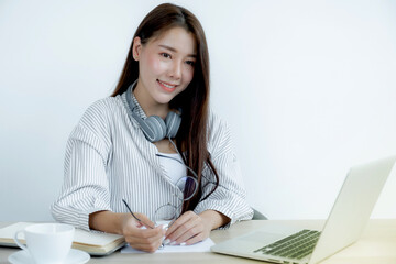 Young woman student taking notes watching laptop study online class video conference education elearning course from home