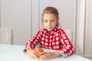 Happy girl sitting at white glass table with pear fruit in hads. concept of healthy eating