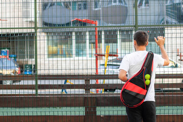 Young man in white T-shirt with tennis racket on artificial football field