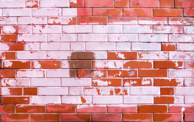Texture of old colored bricks. Close-up of a red-and-white brick wall with old peeling paint. Ancient brick wall background for graffiti. Horizontal background with free space for text