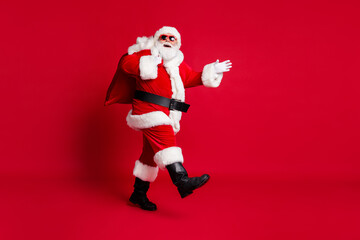 Full length photo of retired old man grey beard hold sack gifts evening walk christmas wear santa...