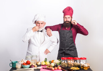 Kitchen. Cooking. Two chefs on kitchen. Serious beared chef man. Delicious food. Male chef in uniform. Chef, cook or baker.