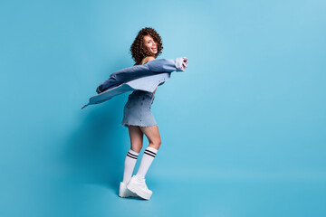 Obraz premium Full size photo nice energetic active lady model turn round fly jacket dancing party clothes brand advert concept wear green crop top denim shirt skirt isolated pastel blue color background
