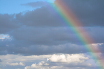 Fototapeta premium Rainbow formed after rain with clouds and blue sky in the background
