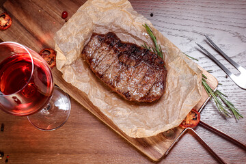 Marbled veal fried on charcoal with vegetables and spices on a wooden board. European cuisine.