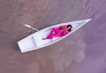 Foto auf Acrylglas Frauen Erstaunliche Traumfee fabelhafte Fantasiestilzusammensetzung schwarze Frau im rosa Anzug, die weißes Boot liegt und Kamera hochschaut. Luftdrohne künstlerische kreative konzeptionelle Vorstellungskraft unterbewusste Psychotherapie