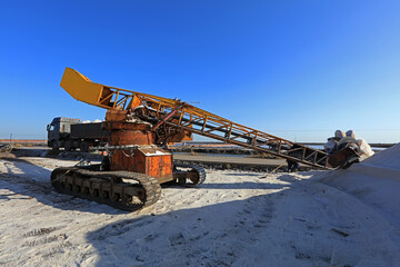machine placing the harvested and washed salt on a conveyor belt. Salt production equipment