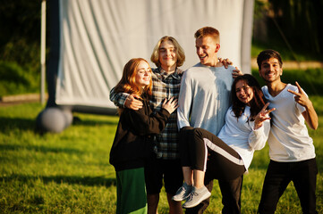 Young multi ethnic group of people watching movie at poof in open air cinema.