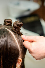 Fototapeta premium Young woman receives process of hairstyle by hairdresser at beauty hair salon