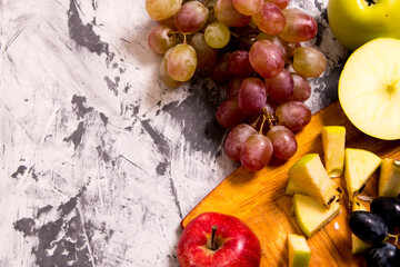 Red and green apples whole and sliced with a bunch of grapes on a cutting Board on a black and white background,close-up,background,Wallpaper,postcard,advertising