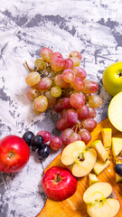 Red and green apples whole and sliced with a bunch of grapes on a cutting Board on a black and white background,close-up,background,Wallpaper,postcard,advertising