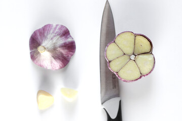 Fresh cut garlic and knife on white background