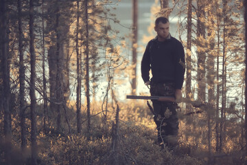hunting man / hunter with a gun hunting in the autumn forest, yellow trees landscape in the taiga