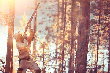 hunting man / hunter with a gun hunting in the autumn forest, yellow trees landscape in the taiga