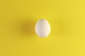 One white egg on a yellow background. The concept of calorie content, life, healthy nutrition, Easter