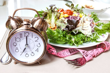 Alarm clock  with salad plate which a Concept of intermittent fasting, breakfast diet and weight...