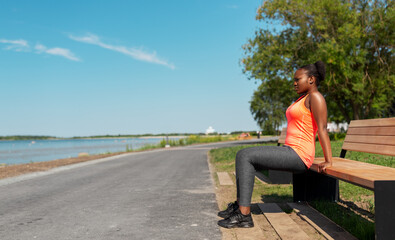 fitness, sport and healthy lifestyle concept - young african american woman exercising with bench at seaside