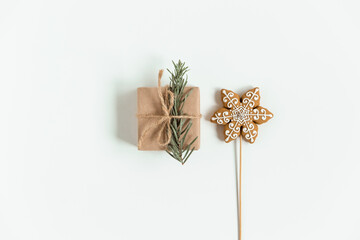 Flat lay of Christmas craft gift box on the white background. Hand made brown paper box with Christmas tree branch and ginger cookies. Close-up view.