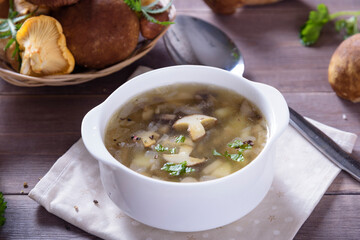 Mushroom soup plate with porcini mushrooms, fresh parsley and pepper on rustic texture background