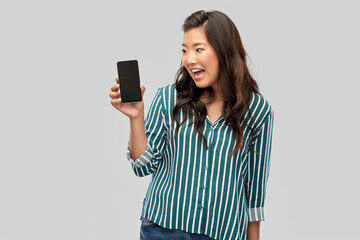 Naklejka premium people and technology concept - happy asian young woman with smartphone over grey background