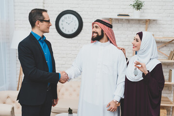 Confident realtor and Arab in kufiya shake hands.