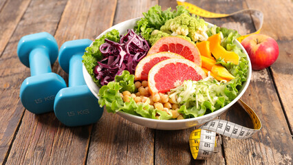 diet food concept- vegetable salad mixed and dumbbell