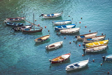 Fototapeta na wymiar Wooden boats moored in the middle of the sea. Small port of fishing boats. Intense blue sea. Different colors.