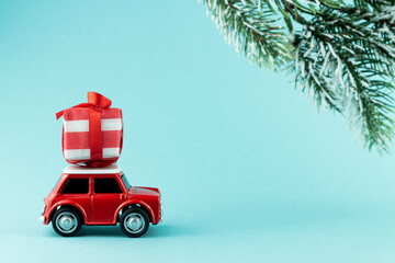 Red toy model car with gift box on blue background. Christmas and Mew year delivery concept