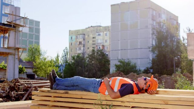 At construction site foreman middle-aged take a nap at lunch time outside beside the construction site he wearing goggles and safety helmet. Shot on ARRI Alexa