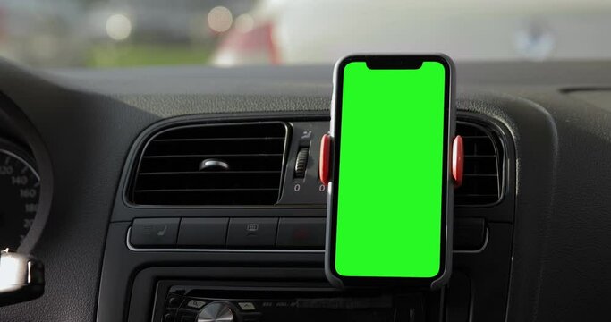 Close up shot of the iPhone 11 Pro Max placed on the car dashboard. A device with a keyed green screen. Autumn fall street, traffic jam. Blank mock-up screen.