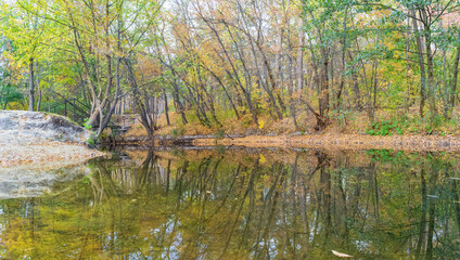 Fototapeta na wymiar Autumn landscape in the forest with a bridge and reflection near the Kharkov river