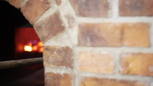chef putting a pizza into a stone oven