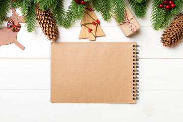 Top view of fir tree, New Year decorations and notebook on wooden background. Christmas concept with copy space