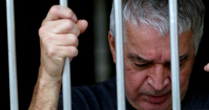 Depressed middle aged man feeling trapped behind bars