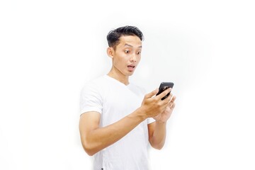 Young asian man holding smartphone and surprised by notification on his smartphone about discount or cash back from online shop. Millennial and business concept. 
