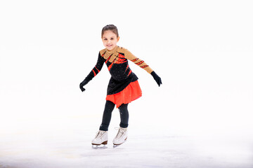 little girl figure skater in red black beautiful dress with smile skates on the ice on an indoor...