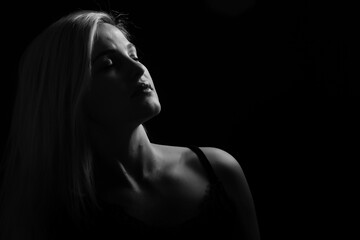 Young beautiful blond glamorous woman in black over dark background