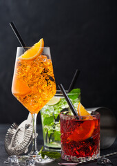 Glasses of spritz,mojito and negroni cocktails with ice cubes and lime and orange slices with mint...