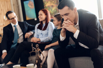Frustrated father, with arms crossed sits on couch