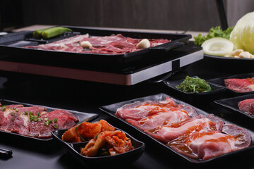 Raw beef slice for barbecue japanese style, yakiniku. Meats are being cooked on stove.