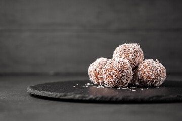 Candy made from dates and coconut shavings without sugar on a slate Board near the copy space