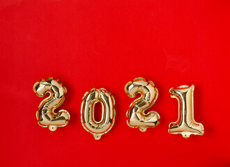 Happy New year 2021 celebration. Gold foil balloons numeral 2021 on red background. Holiday background Happy New Year, flat lay, top view, copy space.
