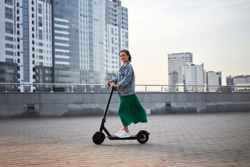 Carefree young woman riding an electric scooter in the city