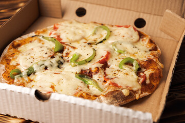 Vegetarian pizza with paprika on wholegrain dough in a cardboard box for delivery