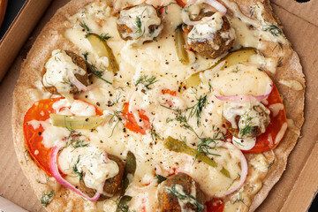 Vegetarian pizza with falafel on whole wheat flour dough in a cardboard box close-up view from above