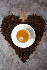 heart shaped cup of black coffee in coffee beans.