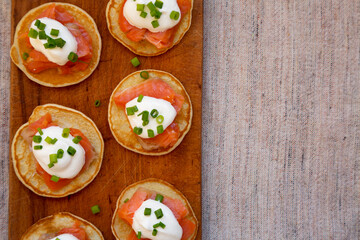 Homemade Blini with Smoked Salmon, Creme and Chives on a rustic wooden board, view from above....